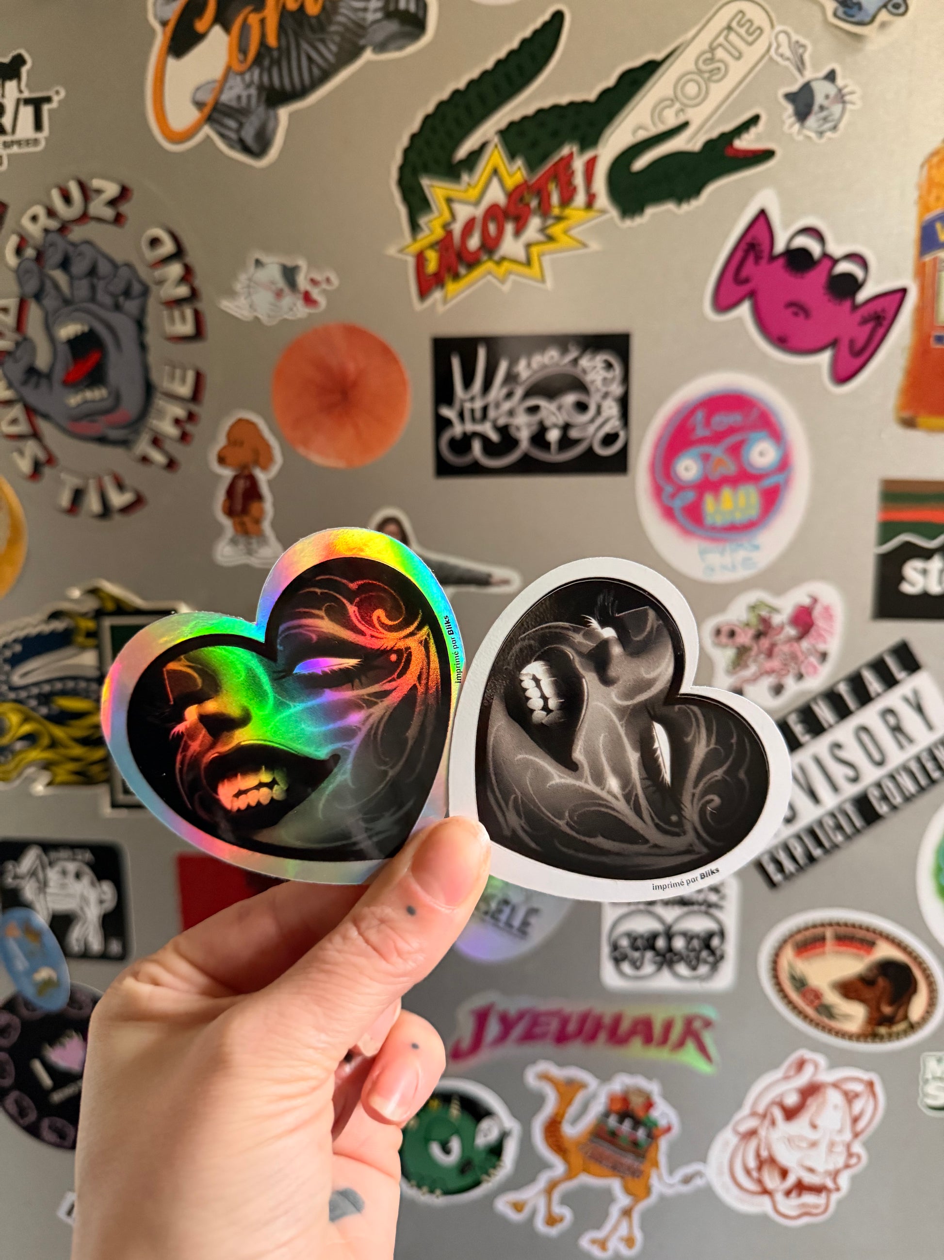 Deux stickers en forme de cœur, dont un holographique et un vinyle blanc, avec illustration noire artistique imprimée par Bliks.